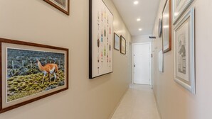 A hallway with framed artwork on the walls, a tiled floor, and a door at the end. - Charming Apt Just 450m From the Beach Emm0202 (Guarapari)