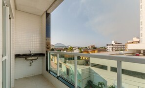 A balcony with a view of a cityscape, a small sink, and a glass railing. - Charming Apt Just 450m From the Beach Emm0202 (Guarapari)