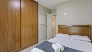 A bedroom with a wooden wardrobe, a bed with white linens, and a grey blanket. - Charming Apt Just 450m From the Beach Emm0202 (Guarapari)