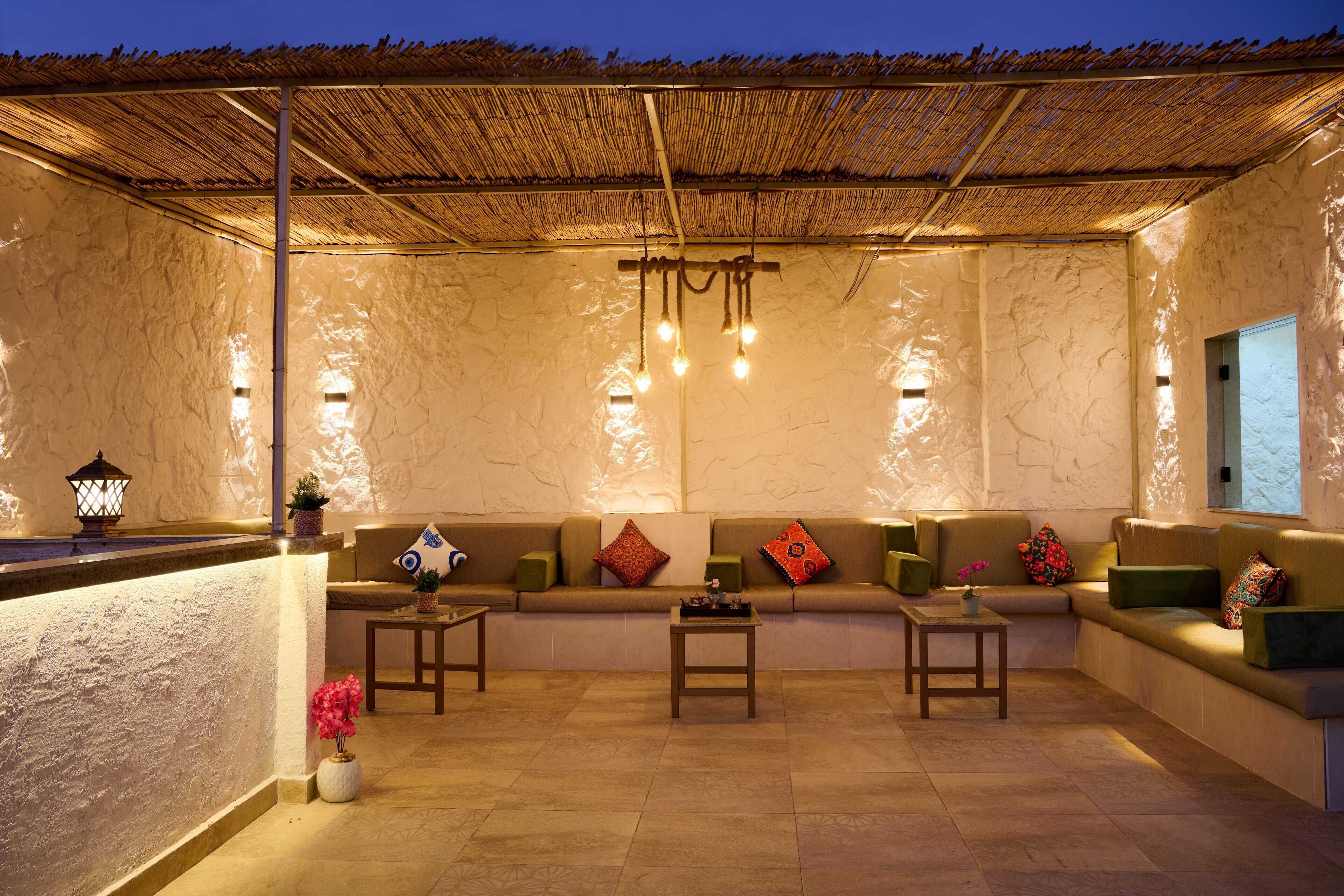 A cozy lounge area with a thatched roof, cushioned seating, and ambient lighting.