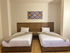 Ein Hotelzimmer mit zwei Einzelbetten, einem Holzkopfstück, einem Nachttisch und einer Wanddekoration.