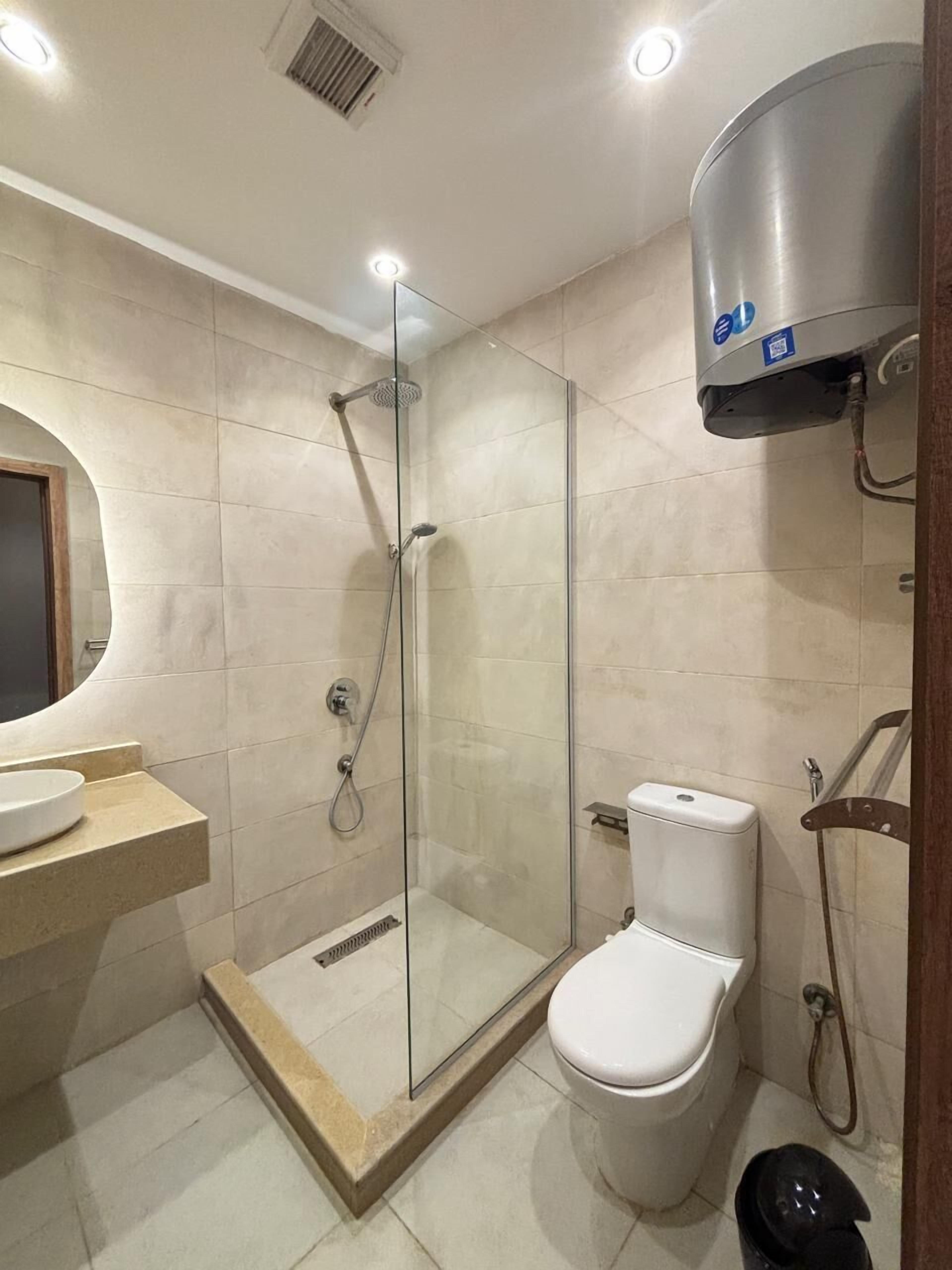 A modern bathroom with a glass-enclosed shower, a toilet, and a sink with a marble countertop.