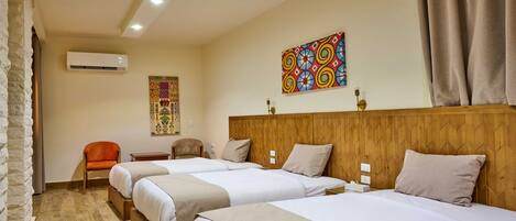 A hotel room with three beds, a wooden headboard, a decorative wall hanging, and a stone wall.