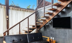A modern interior with a staircase, a black leather sofa, and a TV mounted on the wall. - 3BR Duplex w/ BBQ & Garage Near Beach Emb686 (Bombinhas)