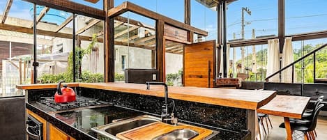 A modern kitchen with a black countertop, stainless steel sink, and wooden cabinets.
