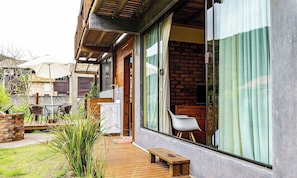 Uma casa moderna com varanda, área de refeições e uma grande janela com cortinas.