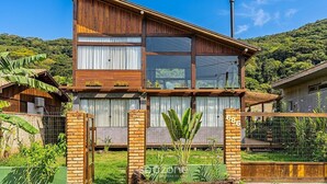 A two-story house with a wooden facade, large windows, and a brick entrance. - 3BR Duplex w/ BBQ & Garage Near Beach Emb686 (Bombinhas)