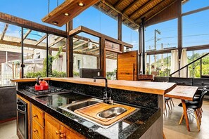 A modern kitchen with a black countertop, stainless steel sink, and wooden cabinets. - 3BR Duplex w/ BBQ & Garage Near Beach Emb686 (Bombinhas)