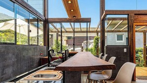 A modern kitchen with a long wooden table, a sink, and a view of the surrounding landscape. - 3BR Duplex w/ BBQ & Garage Near Beach Emb686 (Bombinhas)