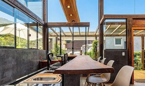 Una cucina moderna con un lungo tavolo di legno, un lavello e vista sul paesaggio circostante.