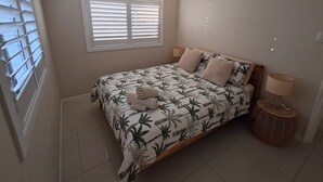 A bedroom with a bed, a ceiling fan, a window with blinds, and a bedside lamp. - Pet Friendly Peninsula (Clontarf)