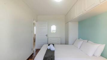 A bedroom with a bed, a nightstand, a window, and a door.