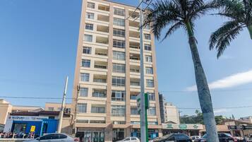 A multi-story building with balconies, a visible clock, and various storefronts including a Suzuki dealership.