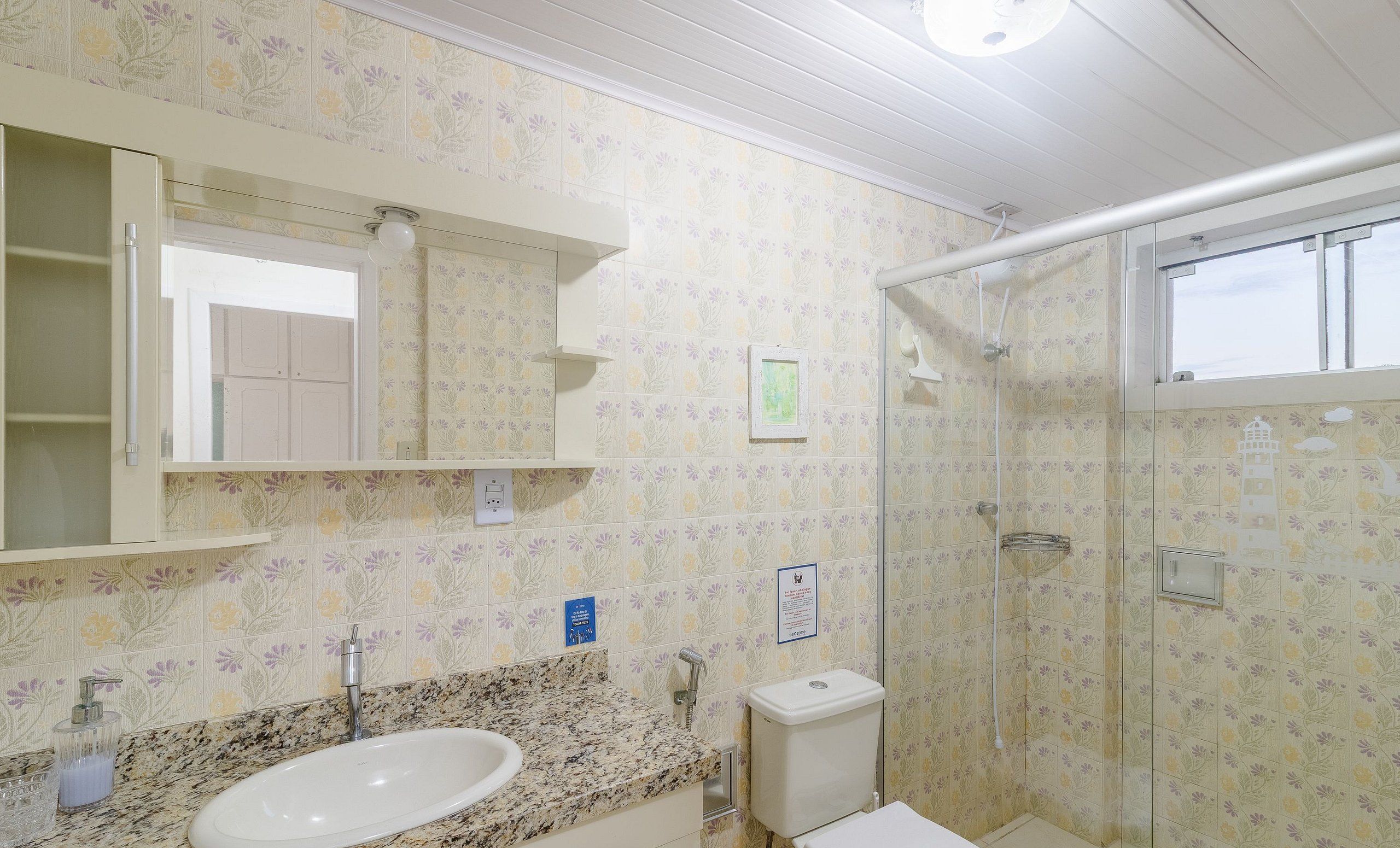 Un baño con lavamanos, espejo, inodoro y ducha.