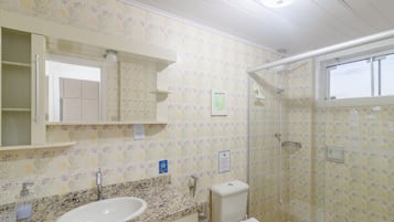 Un baño con lavamanos, espejo, inodoro y ducha.