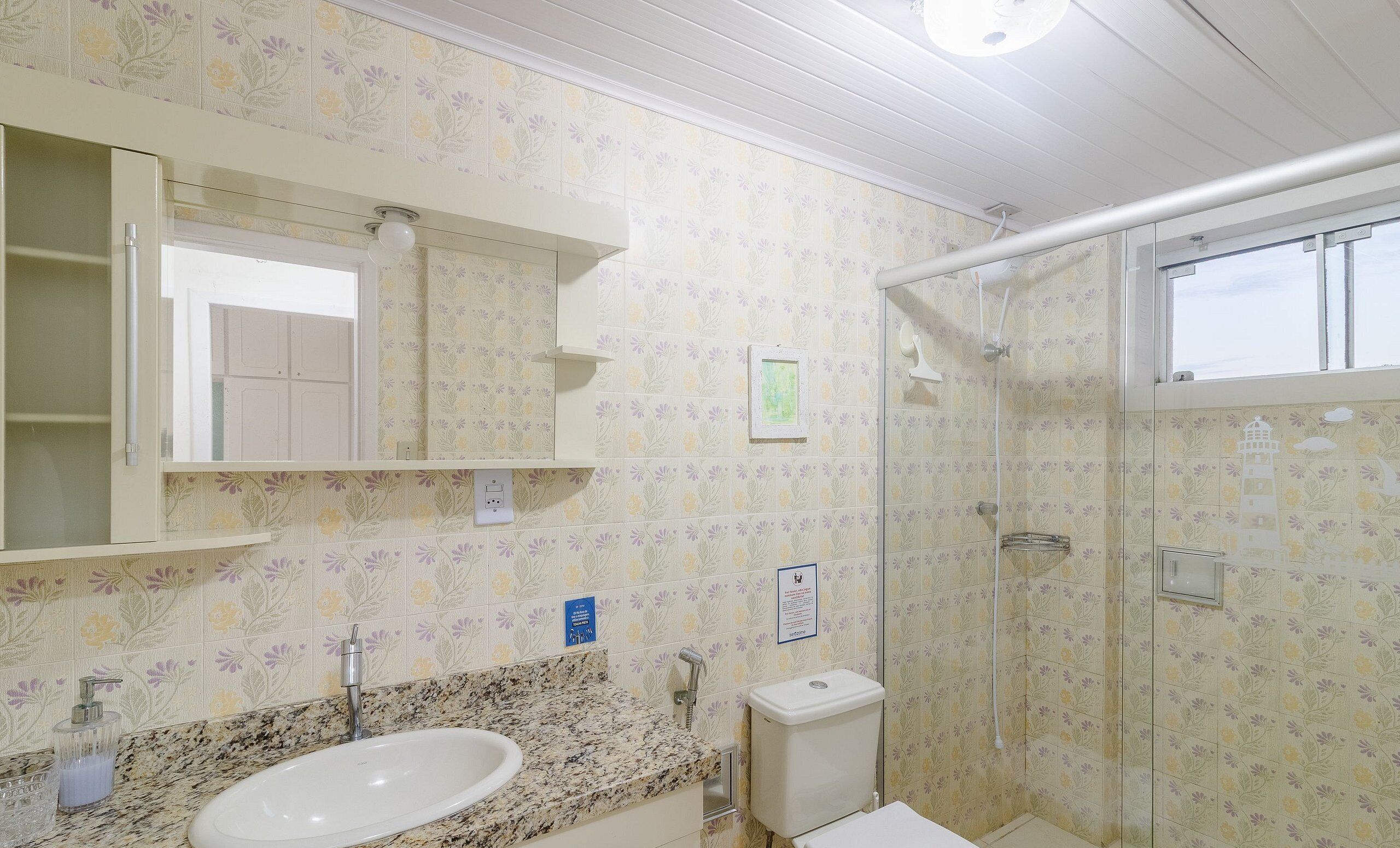Une salle de bain équipée d’un lavabo, d’un miroir, de toilettes et d’une douche.