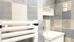 Ein Badezimmer mit weißem Handtuchhalter, Waschbecken und Spiegel.