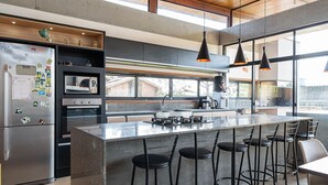 A modern kitchen with a large island, bar stools, and a refrigerator with magnets. - Comfortable House Near Praia do Rosa Egi001 (Imbituba)