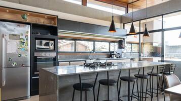 Uma cozinha moderna com uma ilha grande, banquetas e uma geladeira com imãs.
