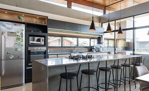 Uma cozinha moderna com uma ilha grande, banquetas e uma geladeira com imãs.