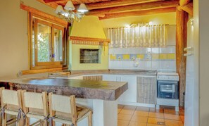 Una cocina con techo de madera, estufa integrada y ventana con vista a la vegetación.