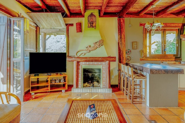 A living room with a fireplace, a television, and a bar area.