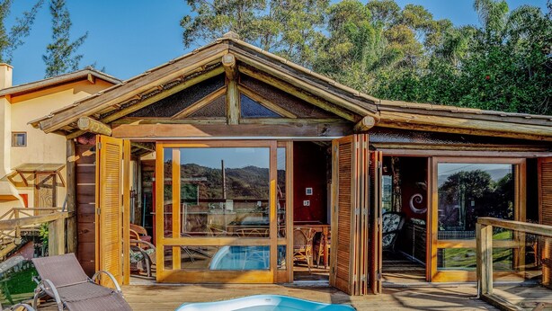 Eine Holzhütte mit einer gläsernen Veranda, einem Pool und Blick auf die umliegende Landschaft.