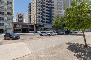 A street view with a restaurant named 'Hamburguesas' and a 'Shopping Mall' sign. - Apartment in a Condominium on the Sand - Efe0803 (Guarapari)