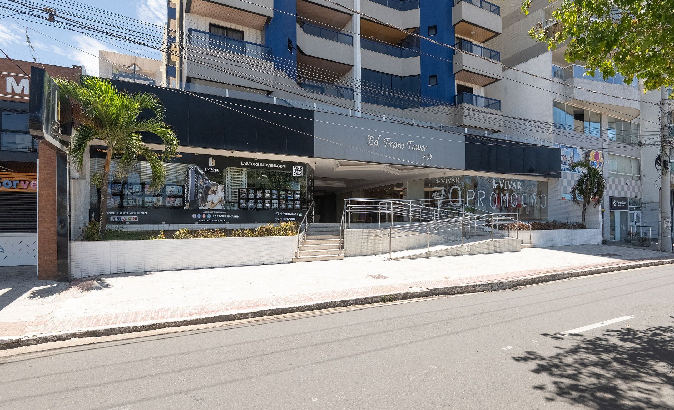 A modern building with a prominent entrance, a staircase leading to the entrance, and a balcony with railings.