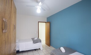 A room with two beds, a wooden wardrobe, a ceiling fan, and a door leading to another room. - Apartment in a Condominium on the Sand - Efe0803 (Guarapari)