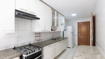 A kitchen with white cabinets, a gas stove, a built-in oven, a sink, and a refrigerator.