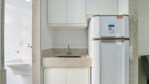 Una kitchenette compacta con un lavamanos integrado, un refrigerador blanco y una encimera de granito.