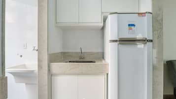A compact kitchenette with a built-in sink, a white refrigerator, and a granite countertop.