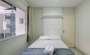 A bedroom with a bed, a window, a wardrobe, and a towel on the bed. - Cozy Apartment Just 300 m From the Beach - Eec0403 (Guarapari)