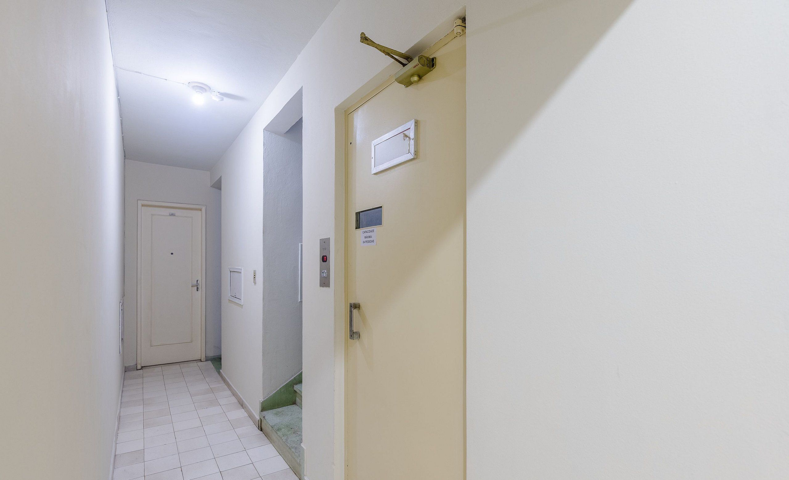 A narrow hallway with a white door on the right, a light switch, and a small window.