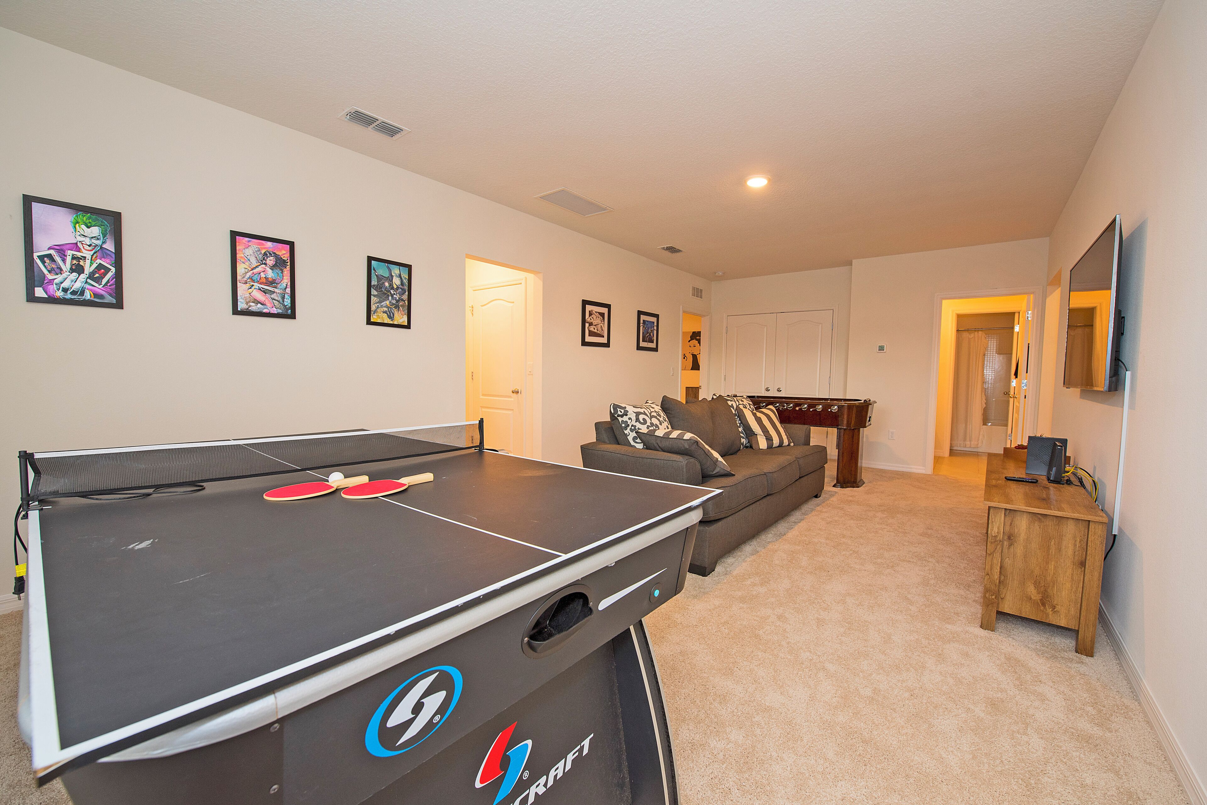 Una sala de estar con mesa de ping pong, sofá y televisor.