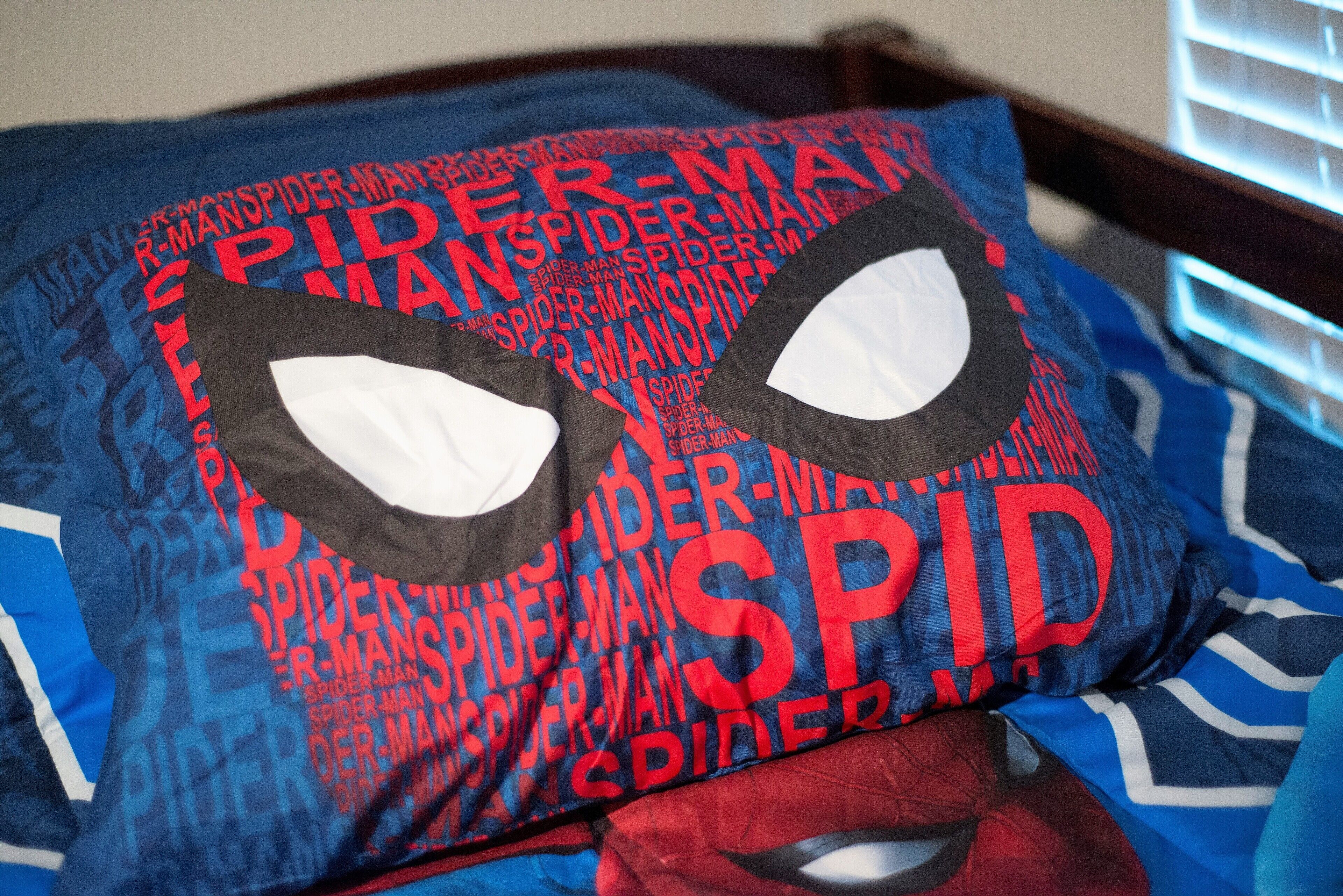 A bed with a Spider-Man themed pillow.