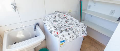 Un baño pequeño con un lavamanos, una lavadora y un cubo verde.