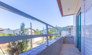 A balcony with a view of a residential area, a tiled wall, and a door. - Beautiful Apart With Balcony and Barbecue Ecu102 (Ubatuba)