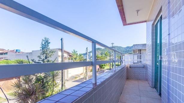 A balcony with a view of a residential area, a tiled wall, and a door. - Beautiful Apart With Balcony and Barbecue Ecu102 (Ubatuba)