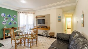 Una sala de estar con una mesa de comedor, sillas, un televisor y un sofá de cuero.
