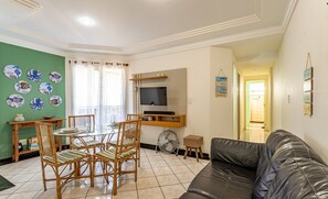 Una sala de estar con una mesa de comedor, sillas, un televisor y un sofá de cuero.