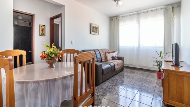A living room with a dining table, sofa, and a TV on a wooden cabinet. - Cozy Apt 350m From Praia do Forte Ecf0306 (Cabo Frio)