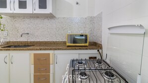 A kitchen with white cabinets, a microwave, a gas stove, and a sink. - Cozy Apt 350m From Praia do Forte Ecf0306 (Cabo Frio)