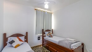 A bedroom with two single beds, a ceiling fan, a window with curtains, and a tiled floor. - Cozy Apt 350m From Praia do Forte Ecf0306 (Cabo Frio)