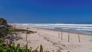 A beach with a sandy shore, a few people, and a clear blue sky. - Barra da Tijuca Vista Mar Lazer e Garagem (Rio de Janeiro)