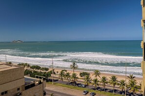 A coastal view with a beach, palm trees, and a distant island.