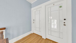 A hallway with two white doors, wooden flooring, and a light blue wall.