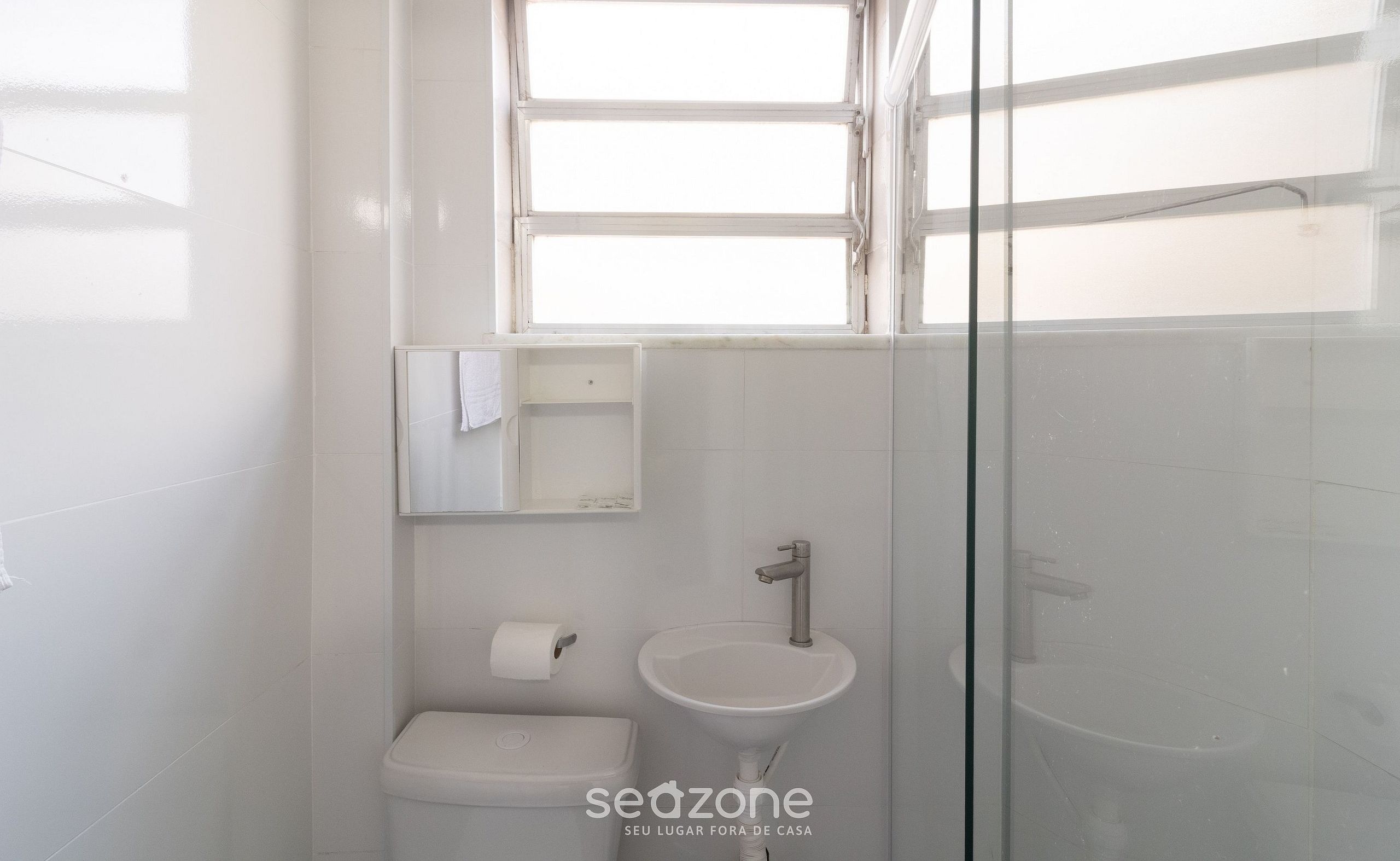 Een badkamer met toilet, wastafel en een douchecabine van glas.