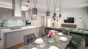 Une cuisine moderne dotée d’un îlot central, un coin repas avec une table en marbre et un salon avec un canapé vert.